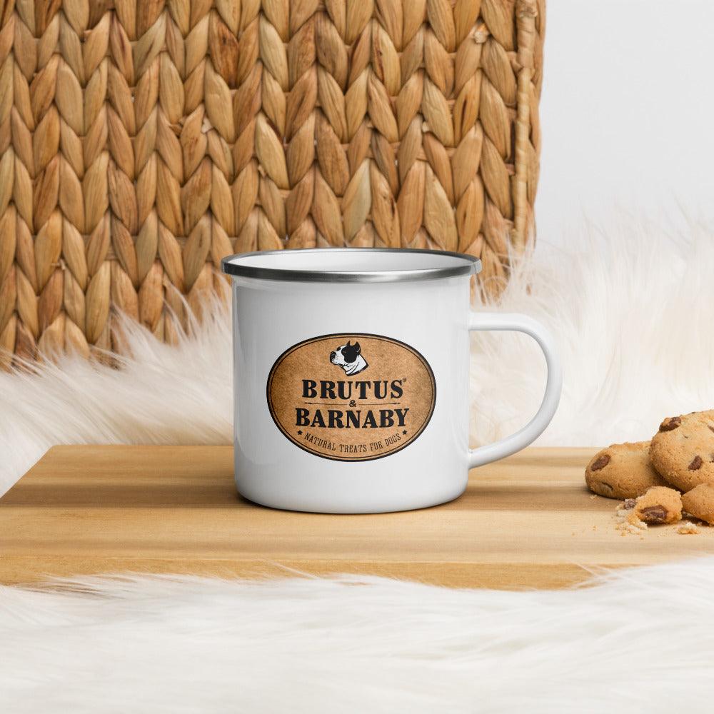 White enamel mug with Brutus & Barnaby logo, dog treats nearby, on wood surface with woven basket background